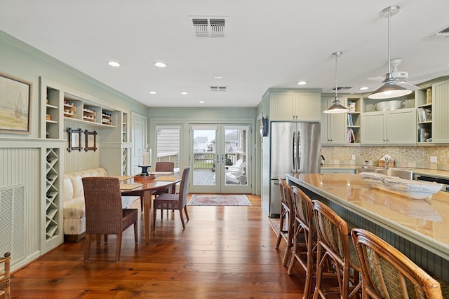 kitchen with visible vents, french doors, freestanding refrigerator, open shelves, and a kitchen bar