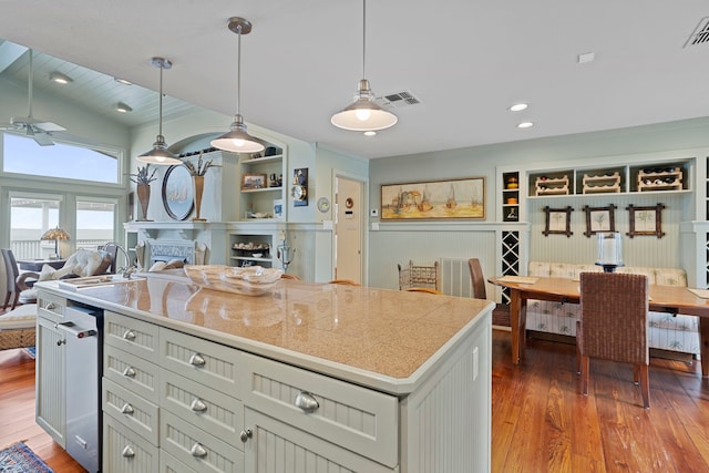 kitchen featuring wood-type flooring, visible vents, a sink, and decorative light fixtures