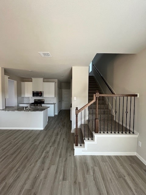 stairway with wood finished floors, visible vents, and baseboards