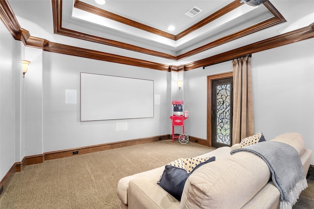 carpeted home theater with a raised ceiling, baseboards, visible vents, and ornamental molding