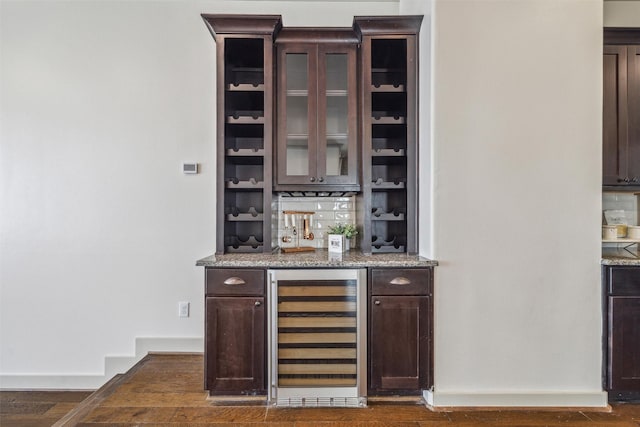 bar with wine cooler, dark wood-style floors, bar, and baseboards