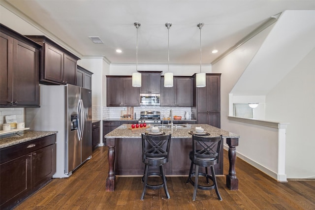 kitchen featuring a breakfast bar area, light stone counters, dark wood-style floors, visible vents, and appliances with stainless steel finishes