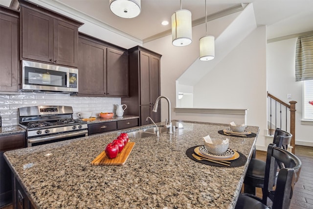 kitchen featuring dark wood finished floors, ornamental molding, decorative backsplash, appliances with stainless steel finishes, and a sink