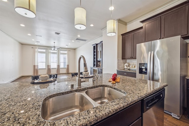 kitchen with crown molding, dark brown cabinetry, dark stone countertops, stainless steel appliances, and a sink