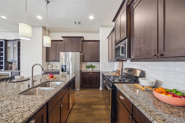 kitchen with pendant lighting, appliances with stainless steel finishes, light stone countertops, and a sink