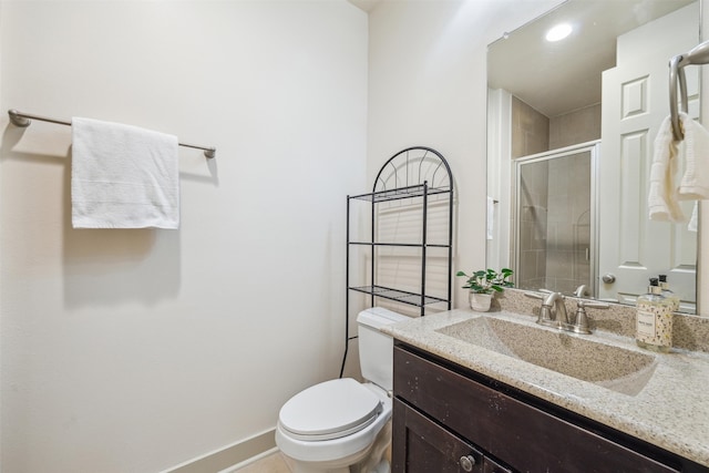 bathroom with baseboards, vanity, a shower stall, and toilet