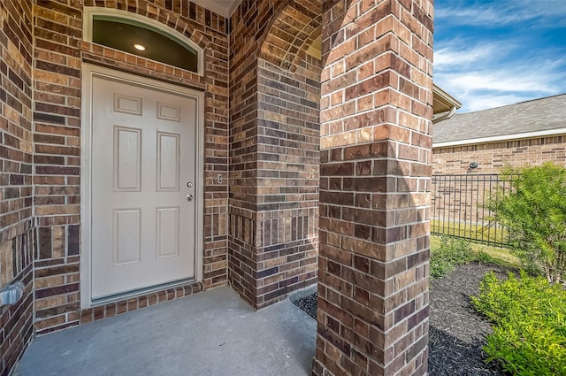 doorway to property with brick siding and fence