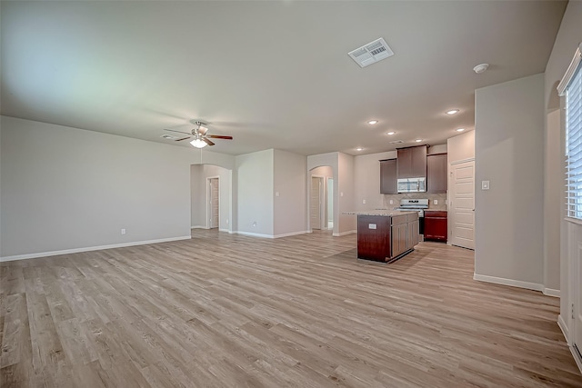 kitchen featuring arched walkways, visible vents, appliances with stainless steel finishes, open floor plan, and a kitchen island