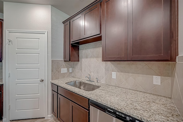 kitchen with light stone counters, tasteful backsplash, stainless steel dishwasher, a sink, and dark brown cabinetry