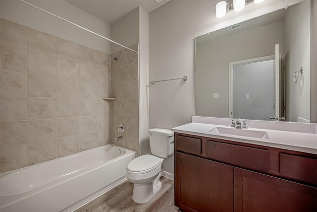 full bath with shower / tub combination, toilet, wood finished floors, visible vents, and vanity