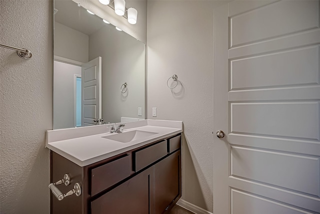 bathroom with a textured wall and vanity