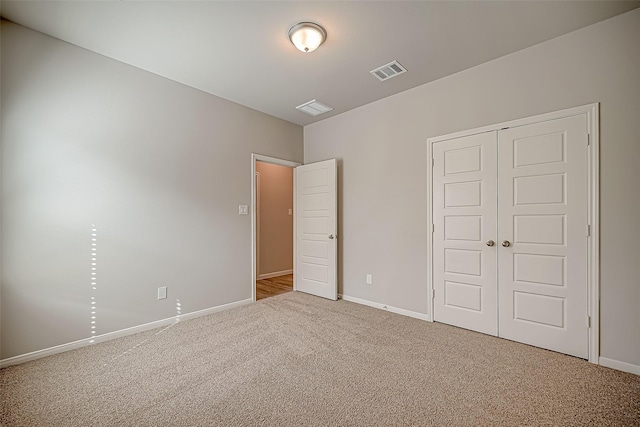 unfurnished bedroom featuring carpet floors, a closet, visible vents, and baseboards