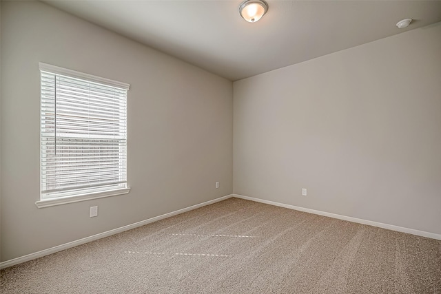 carpeted spare room featuring baseboards