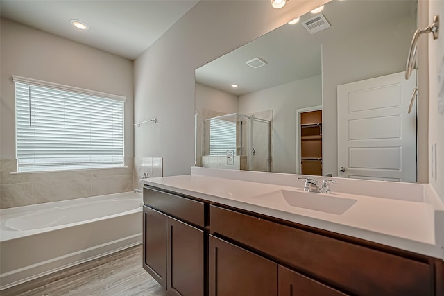 full bath featuring a walk in closet, visible vents, a stall shower, vanity, and wood finished floors