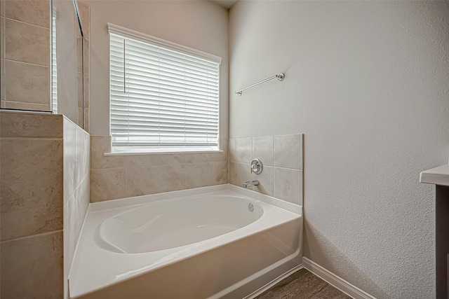 bathroom with a garden tub and a textured wall