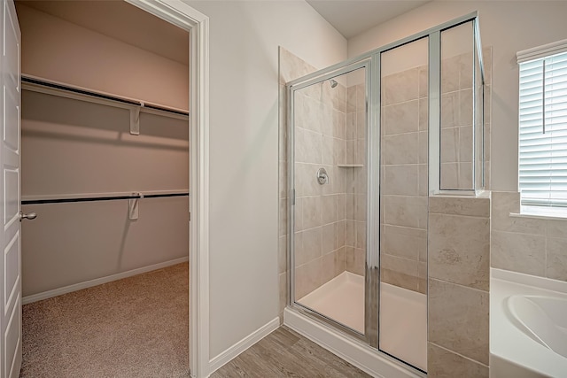 full bath with a shower stall, a spacious closet, baseboards, and a bath