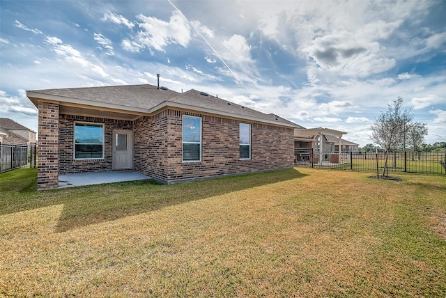 rear view of property with brick siding, a fenced backyard, and a yard