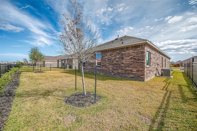 view of yard with a fenced backyard and central AC unit