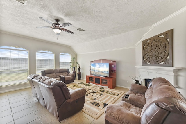 living area featuring light tile patterned floors, visible vents, ceiling fan, vaulted ceiling, and a fireplace