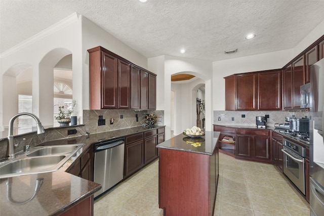 kitchen with a center island, stainless steel appliances, backsplash, a sink, and a peninsula