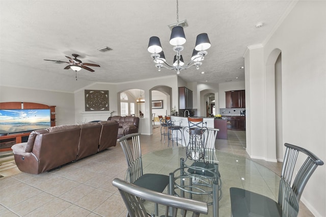 dining space featuring light tile patterned floors, visible vents, arched walkways, and ornamental molding