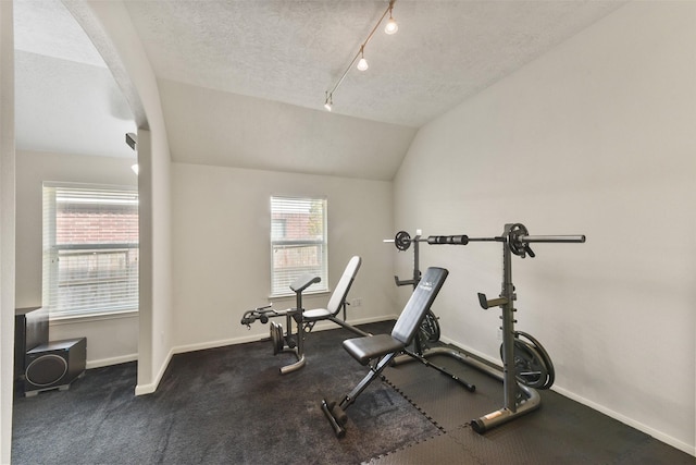 workout room featuring track lighting, vaulted ceiling, a textured ceiling, and baseboards