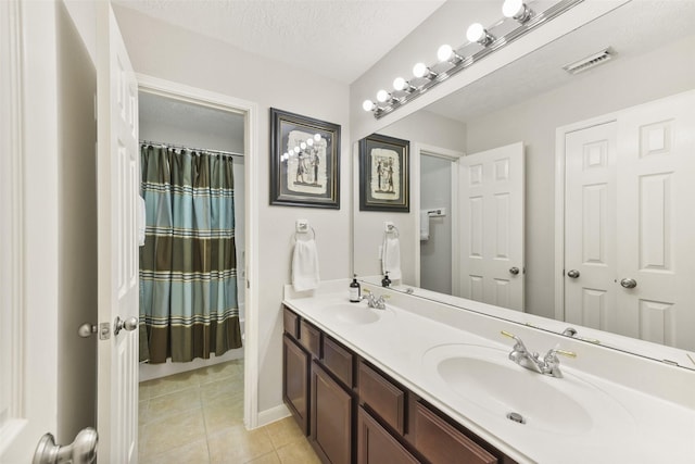 bathroom with tile patterned flooring, visible vents, a sink, and a textured ceiling