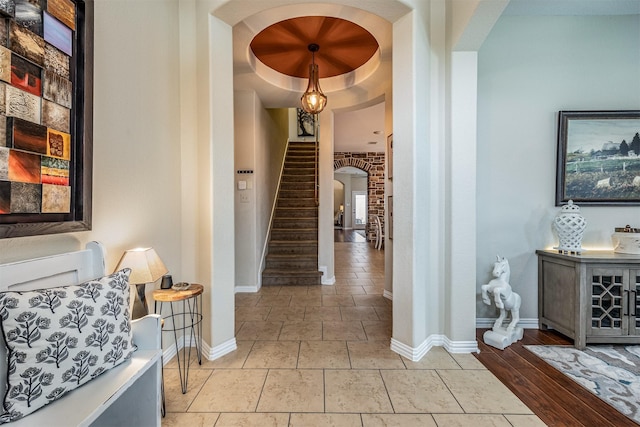 corridor with stairway, baseboards, and arched walkways