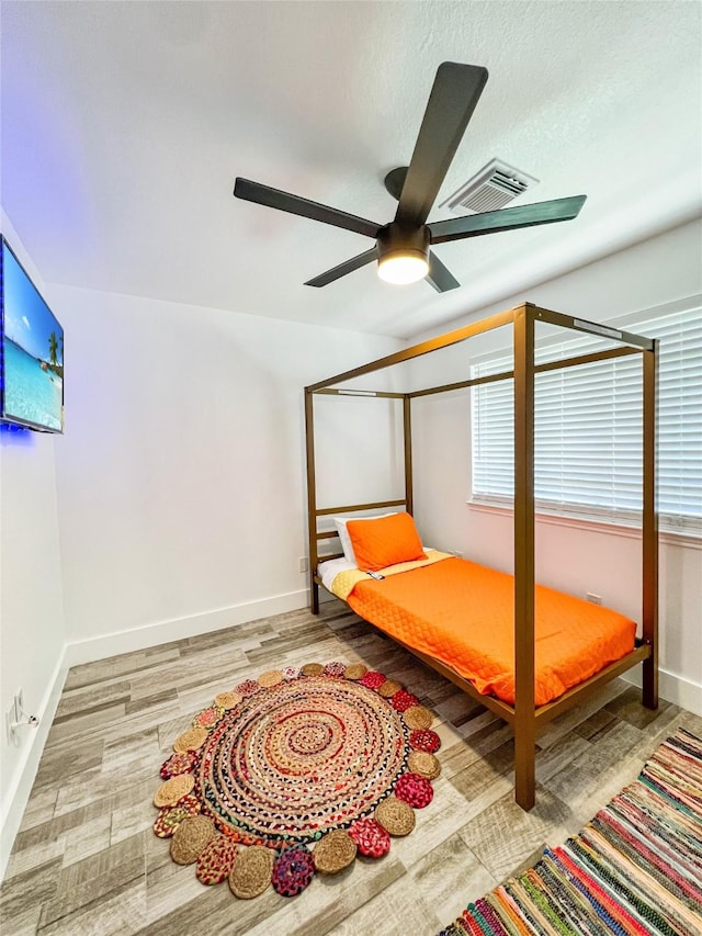 bedroom with baseboards, wood finished floors, visible vents, and a ceiling fan