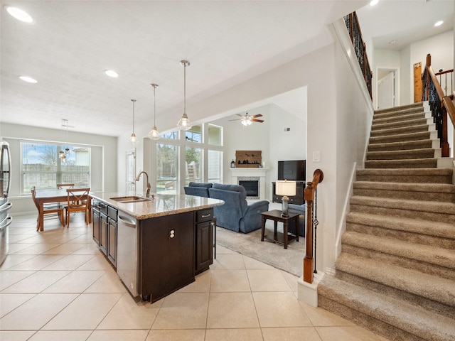 kitchen featuring hanging light fixtures, a sink, an island with sink, dark brown cabinets, and dishwasher