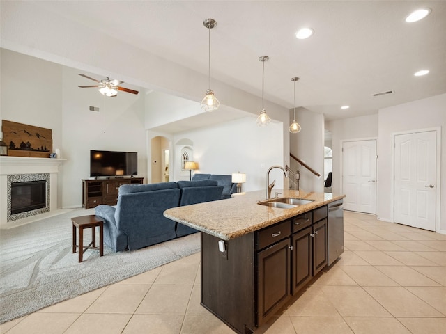 kitchen with dishwasher, open floor plan, a fireplace, pendant lighting, and a sink