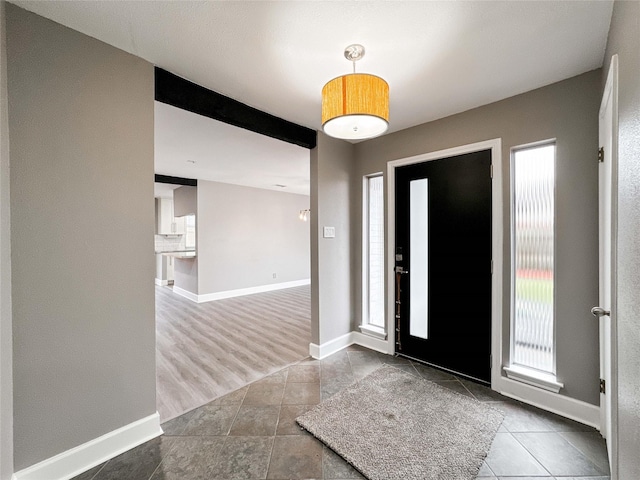 foyer entrance featuring plenty of natural light, tile patterned floors, and baseboards