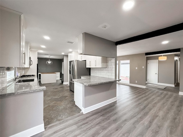 kitchen featuring a peninsula, a sink, white cabinets, stainless steel refrigerator with ice dispenser, and tasteful backsplash