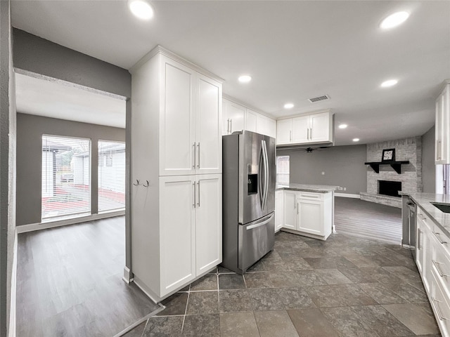 kitchen with recessed lighting, white cabinets, a fireplace, and stainless steel fridge with ice dispenser