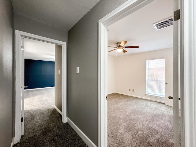 corridor featuring carpet floors, visible vents, and baseboards