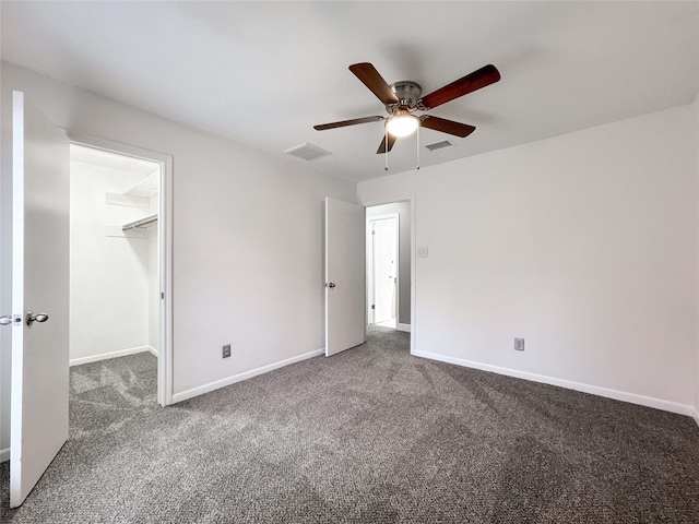 unfurnished bedroom with dark colored carpet, visible vents, and baseboards