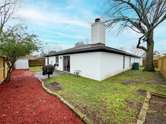 back of property with brick siding, a yard, central air condition unit, a patio area, and a fenced backyard