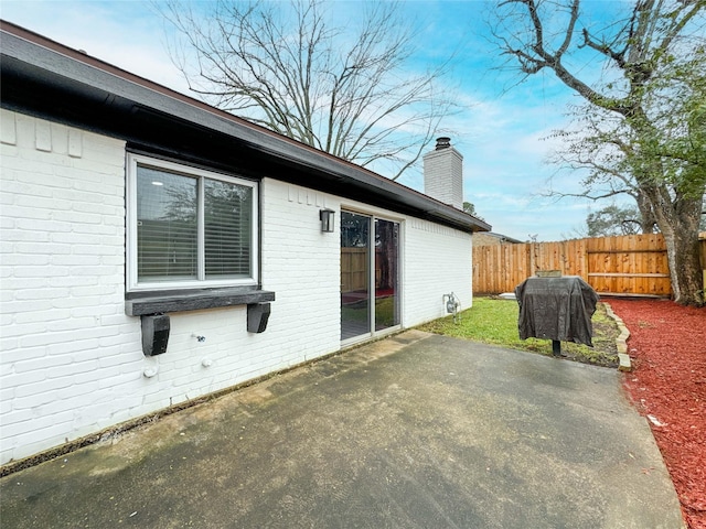 back of house with brick siding, a patio, a chimney, and fence