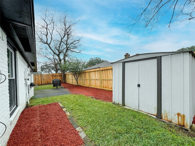 view of yard featuring an outbuilding, a patio, a storage unit, and a fenced backyard