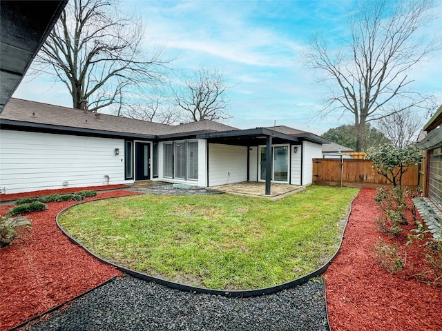 back of property with a fenced backyard, a patio, and a yard