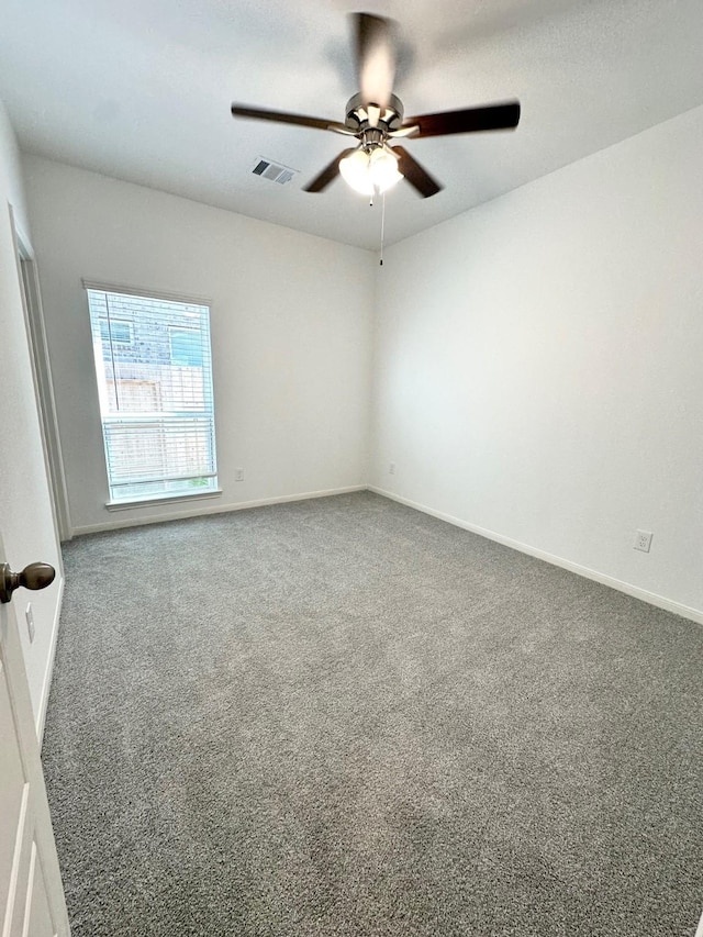 carpeted spare room featuring baseboards, visible vents, and a ceiling fan