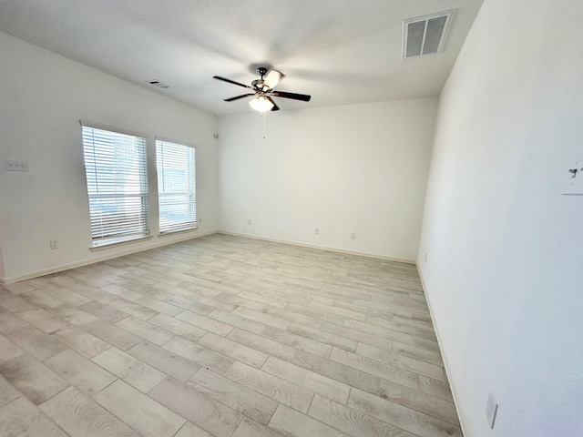 unfurnished room with a ceiling fan, light wood-type flooring, visible vents, and baseboards