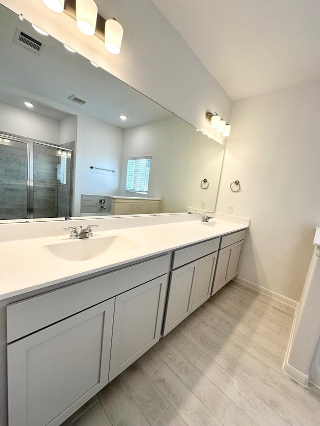 bathroom featuring double vanity, a stall shower, visible vents, and a sink