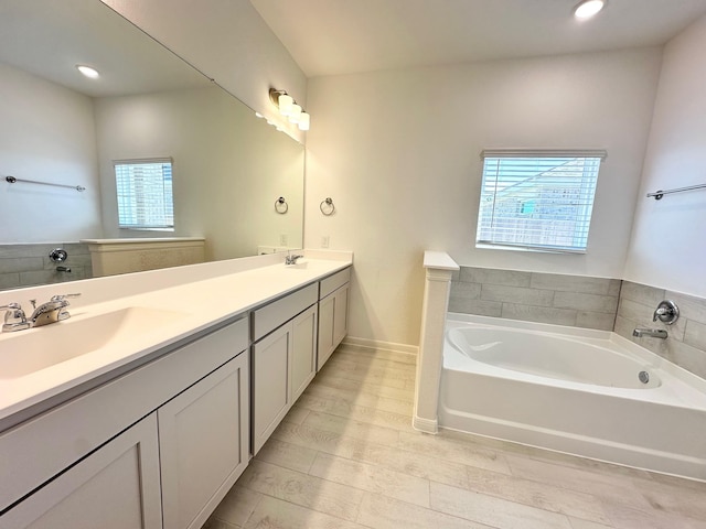 full bath with a bath, double vanity, baseboards, and a sink