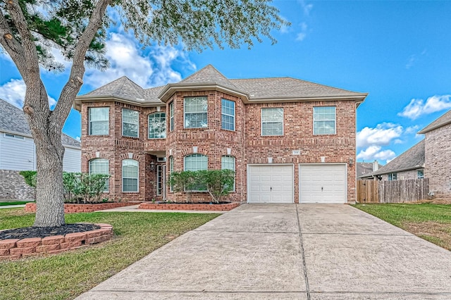 traditional home with fence, a front lawn, concrete driveway, and brick siding