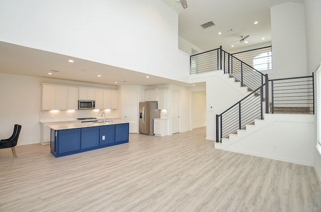 kitchen with visible vents, an island with sink, appliances with stainless steel finishes, light countertops, and white cabinetry