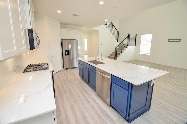 kitchen featuring visible vents, stainless steel appliances, blue cabinetry, white cabinetry, and a sink