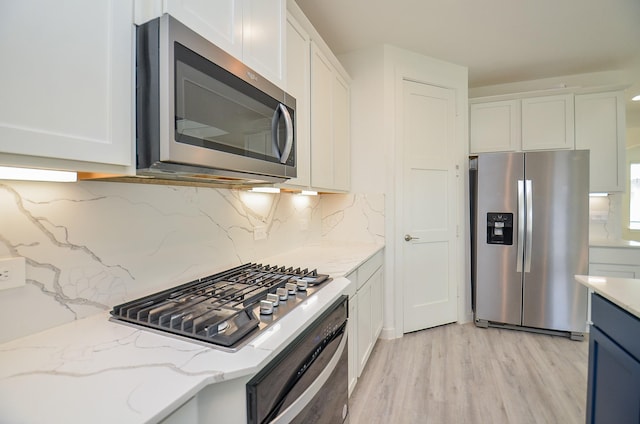 kitchen with appliances with stainless steel finishes, white cabinetry, and light stone countertops