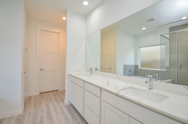 full bath featuring recessed lighting, a shower stall, a sink, and wood finished floors