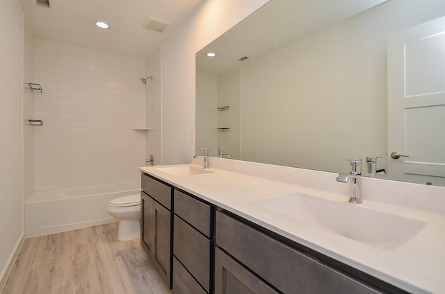 full bath with toilet, visible vents, a sink, and wood finished floors